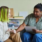 African female school psychologist supporting sad teenage girl during her difficult situation at school