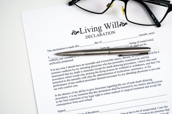 Living will declaration form with glasses and silver pen.